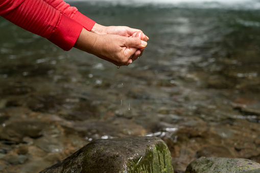 Female hands scooping cold water from the river. Azores