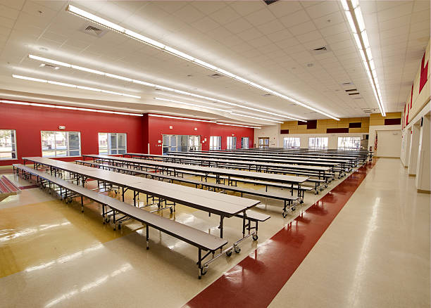 Long tables in an empty red and beige high school cafeteria Cafeteria at High School in Central Florida. cafeteria stock pictures, royalty-free photos & images