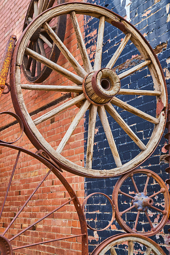 Image of Old carriage wheels in collage against brick building