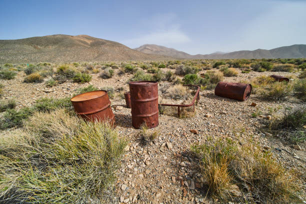 istock Old metal barrels in desert plains by mountains 1491040686