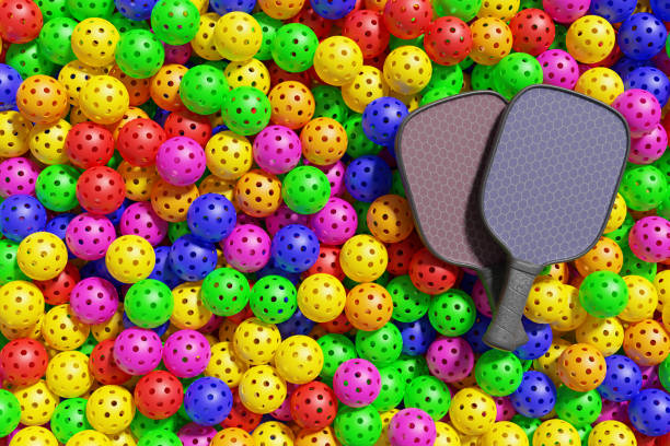 pickleball. due racchette giacciono su una grande pila di palle sportive multicolori. rendering 3d - plastic hole heap close up foto e immagini stock
