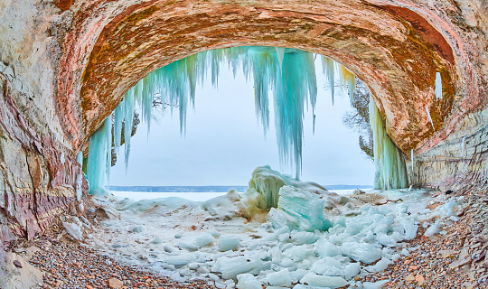 Image of Opening to large ice cave in Michigan with blue and green icicle formations