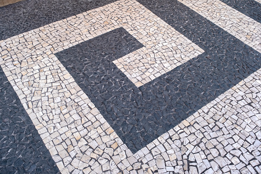 Portuguese traditional black and white pavement made from calcada tiling. Fragment of sidewalk paving in Funchal, Madeira island