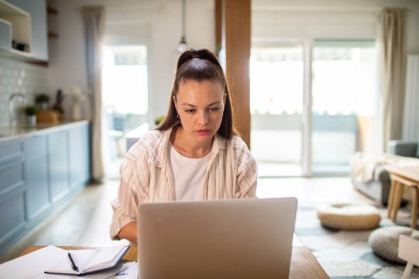 istock Young woman going over her finances at home while using her laptop 1491043446