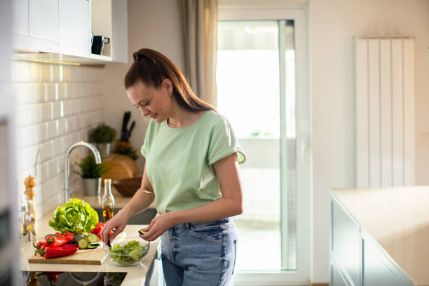 istock Young woman cutting and preparing vegetables in a kitchen at home 1491043810