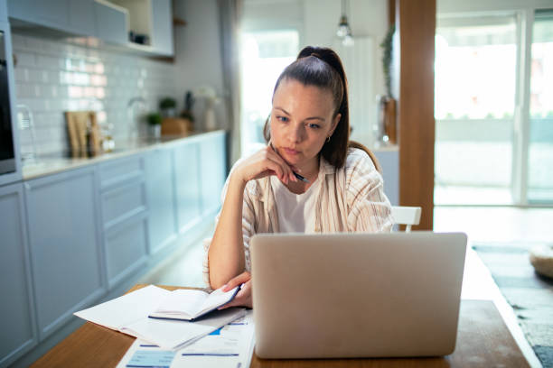 istock Young woman going over her finances at home while using her laptop 1491043933