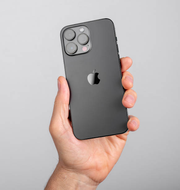 mão segurando iphone 14 pro max back view com câmera e logotipo preto da maçã - luggage hold - fotografias e filmes do acervo