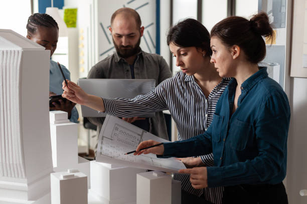 istock Team of diverse architects discussing blueprint plans 1491044115