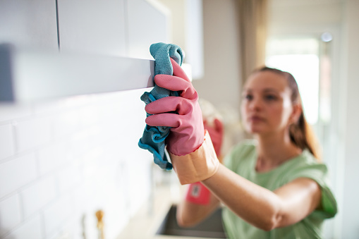 Close up of a young woman using cleaning products to clean the kitchen in her home