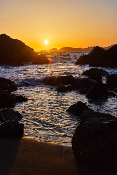 istock Sandy beach with waves over rocks next to vibrant sunset 1491044412