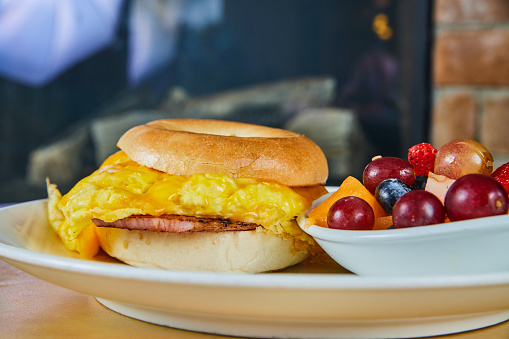 Image of Simple breakfast bagel sandwich with fruit bowl next to fireplace