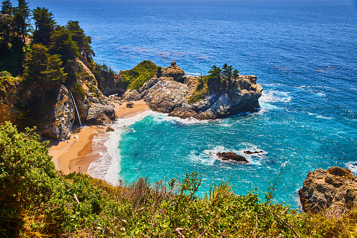Image of Small ocean cove surrounded by cliffs, waterfall, and sandy beaches