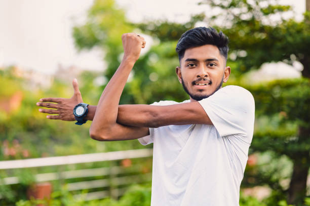 istock Athlete man stretches his arms at park before training workout 1491046388