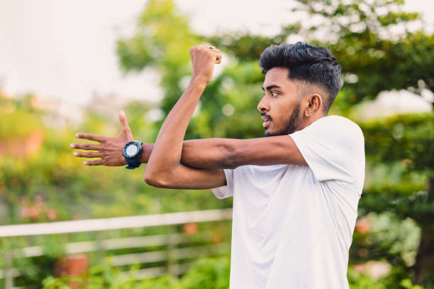 istock Athlete man stretches his arms at park before training workout 1491046398