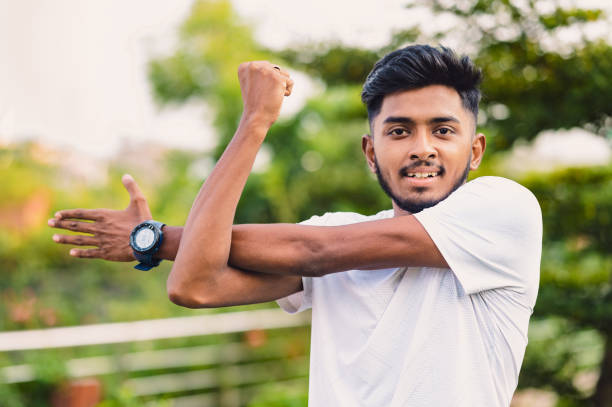 istock Athlete man stretches his arms at park before training workout 1491046400