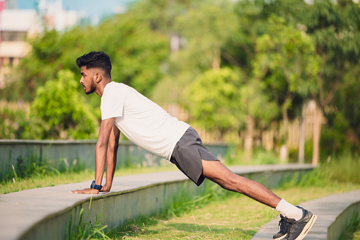 Outdoor image of Young sports man doing push-ups exercise at the stairs of park. Concept of Healthy lifestyle and exercise.