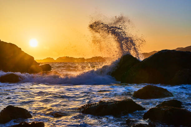 istock Stunning splash of ocean waves off large rocks at sunset 1491047927