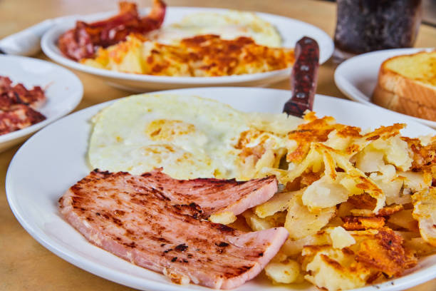istock Table of breakfast with focus on ham, potatoes, and eggs 1491049124