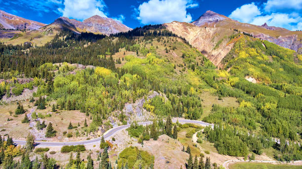 istock Mountain covered in fall aspen and pine trees with road cutting through 1491049580