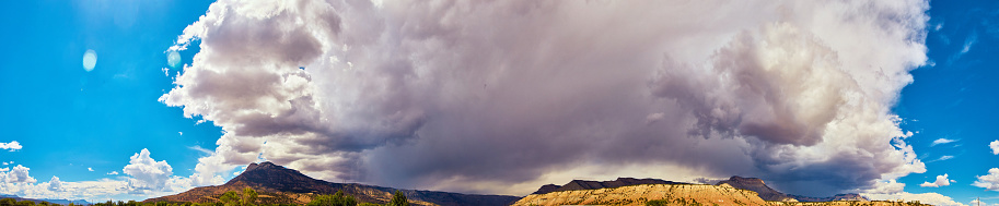 Image of Panorama of large mountain range against immense storm clouds covering mountains in shadow
