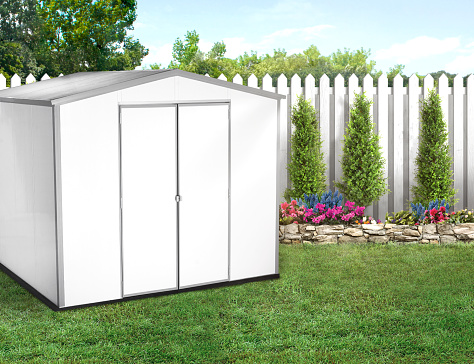 White shed in a backyard with green grass and wood fence