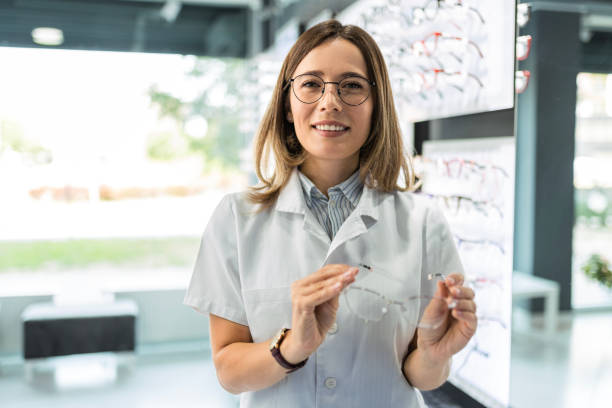 istock Optician looking at the camera smiling in optical store holding eyewear 1491054874