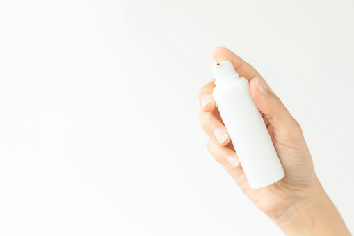 Hand is showing moisturizer bottle with white mockup space in front of white background.