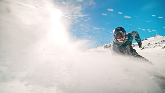 SLOW MOTION Male friends moving downhill while snowboarding on snow against sky. Men are on snowcapped mountain on sunny day. They are enjoying winter sport.