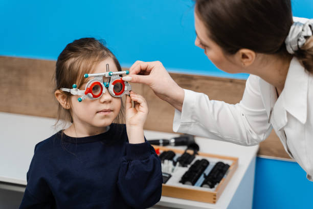 istock Pediatric ophthalmologist is wearing trial frame glasses on child. Examination with ophthalmologist for selection of trial glasses frame to examine eye visual system. 1491058543