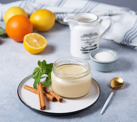 Delicious panna cotta or vanilla pudding with citrus fruits in a jar on a light background with  ingredients. Homemade healthy sweet food.