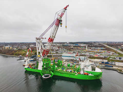 Aerial view of a heavy lift vessel used in offshore wind farm construction docked on an overcast afternoon.