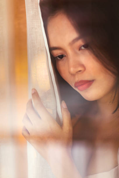 istock A young woman standing at a window looking out 1491062963