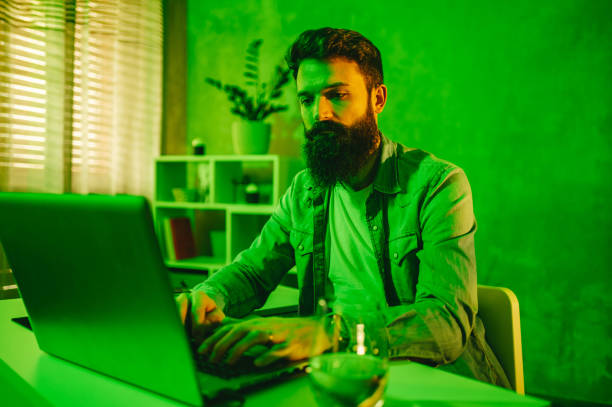 istock A focused programmer is typing on a laptop while sitting in a green-lighted room. 1491063217