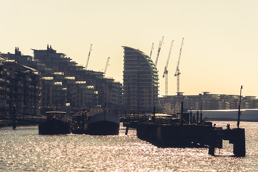 Old boats by the river Thames, with modern buildings in Chelsea London