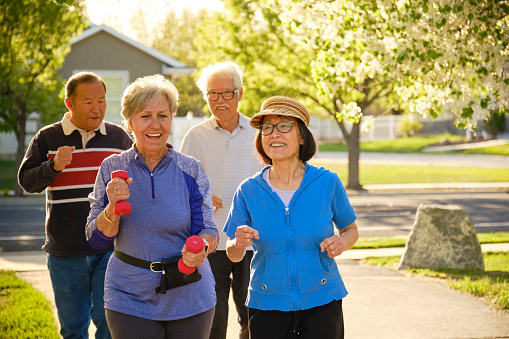 A group of senior aged people power walking in a park.