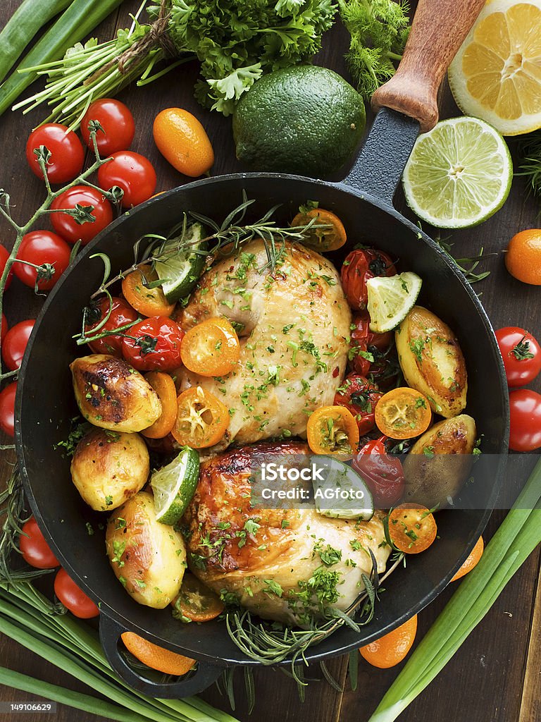 Dinner Frying pan with roasted chicken, vegetables, herbs and fruits. Shallow dof. Baked Stock Photo