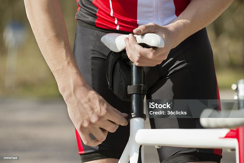 Man Adjusting Seat Of Bicycle Midsection of man adjusting the seat of his bicycle Bicycle Seat Stock Photo