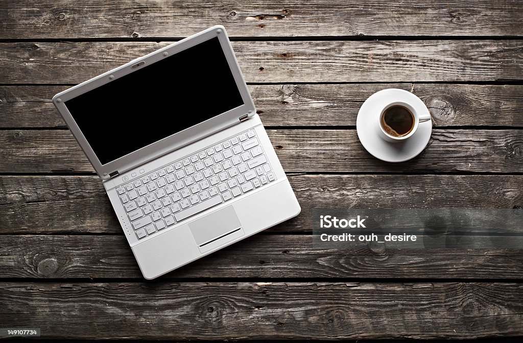 White laptop and coffee cup on wooden table White laptop with coffee cup on old wooden table. Top view. Blank Stock Photo