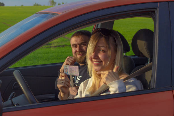 Holding in hand obtained copyright woman smiling joyfully while sitting in the car. A woman passed a driving test with an instructor. The woman got her copyright and is very happy. Holding in hand obtained copyright woman smiling joyfully while sitting in the car. A woman passed a driving test with an instructor. The woman got her copyright and is very happy.. showing their international copyright stock pictures, royalty-free photos & images