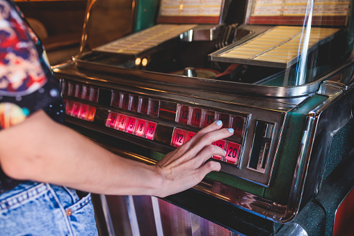 Vintage American music jukebox with illuminated buttons, process of choosing song composition, retro old-fashioned juke-box with vinyl discs musical box machine in a cafe diner restaurant