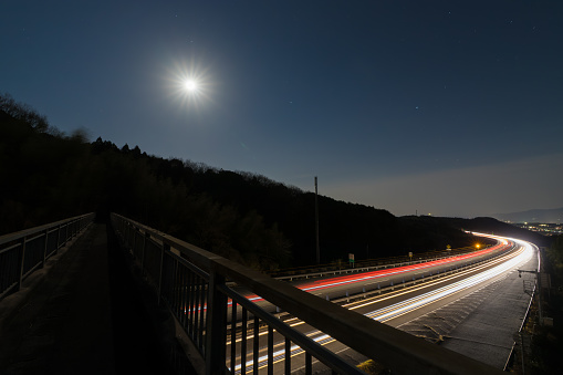 it is Light trails of cars on highway in moonlit night