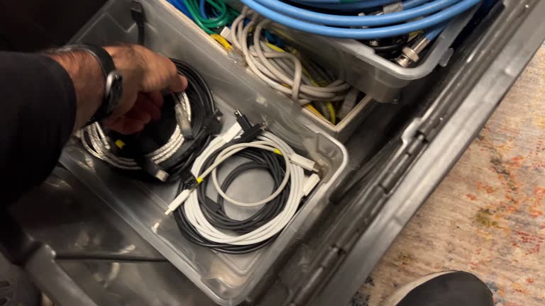 Overhead Shot of a Man's Hands Picking up, Moving, and Organizing a Large Box with Smaller Boxes Inside It Filled with Assorted Computer and Audio Cables