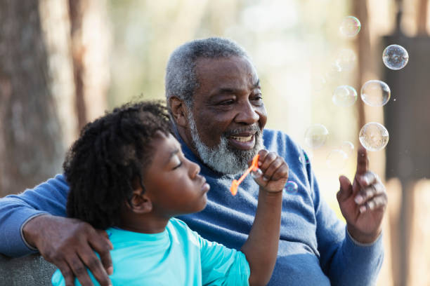 istock Senior man, grandson at park blowing bubbles with wand 1491093685