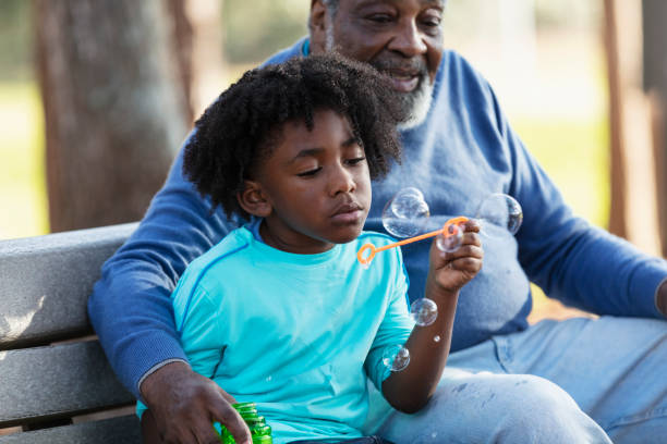 istock Senior man, grandson at park blowing bubbles with wand 1491093687