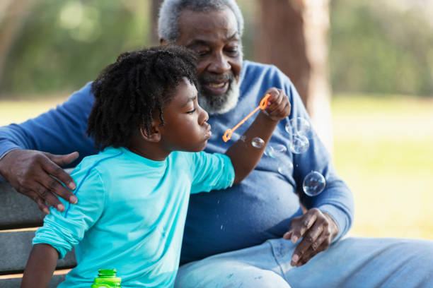 istock Senior man, grandson at park blowing bubbles with wand 1491093692