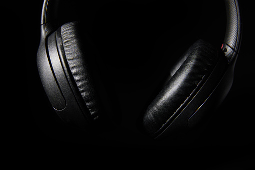 close up photo of black headphones shot in studio in low key lighting.