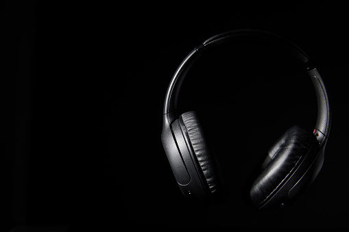 Still life of professional wireless headphones floating in the air on a black background with copy space.