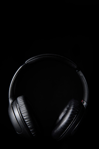 Still life of black headphones floating in the air on a dark background