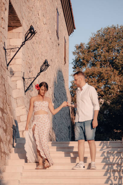 istock Young couple walking down the stairs, while holding hands, looking at each other and smiling 1491098072