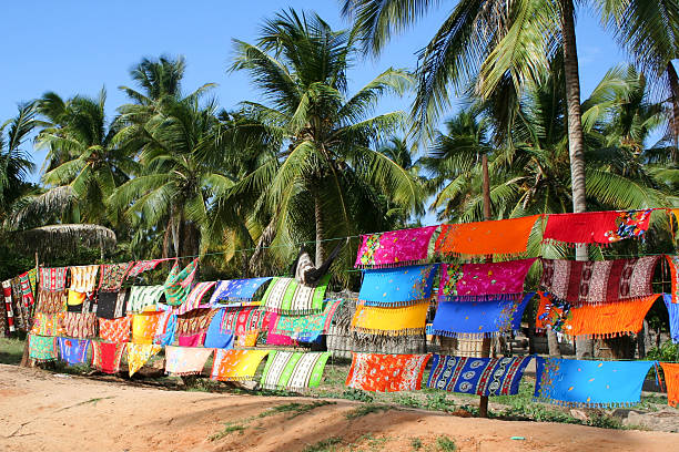 Colorful Sarongs at informal market hanging below coconut palm trees Sarongs being advertised in the Inhambane area, Mozambique. These colourful displays and informal markets or shops line the tourist roads on the way to Barra. These are sold by the local community. The coconut palms trees are common in these areas. The image is a typical scene that a tourist in the area would experience mozambique stock pictures, royalty-free photos & images